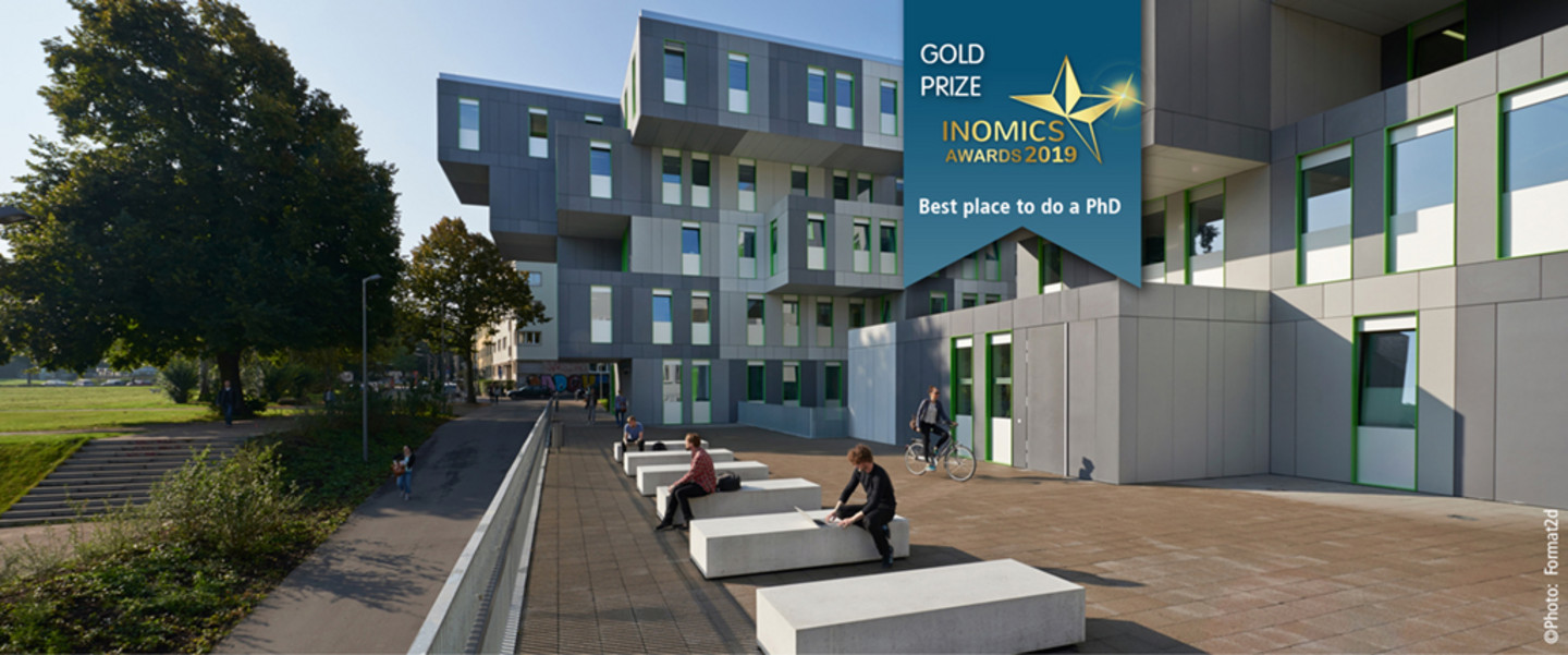 Backside of the SSC-Building consisting of many nested white cubes. On an inset banner, the text: Gold Prize Inomics Awards 2019 - Best Place to do a PhD